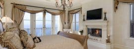 traditional-master-bedroom-with-fireplace-ocean-views-and-balcony