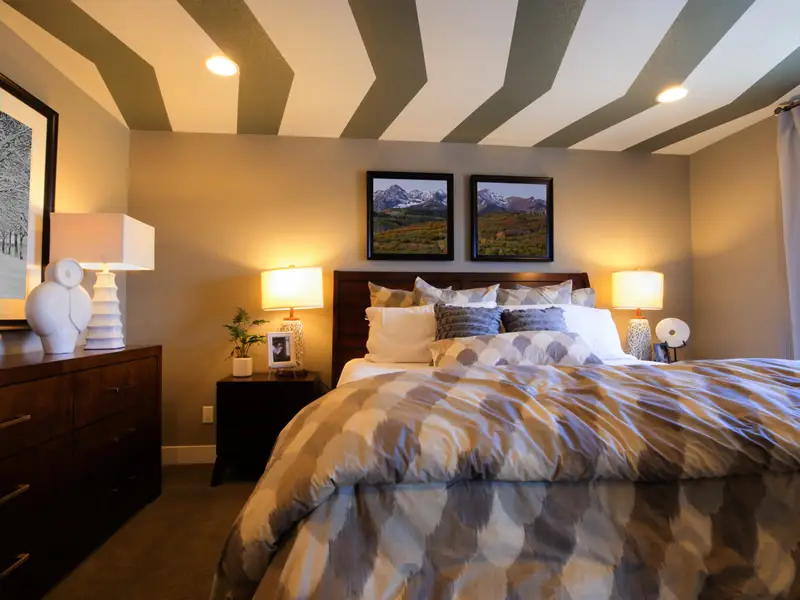 Bedroom with striped ceiling, white lamp and two picture frames 