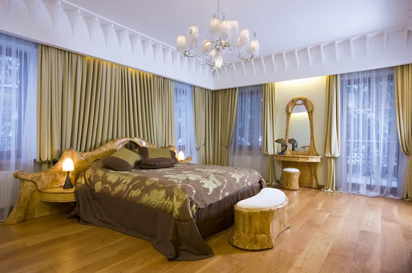 Bedroom with gold drapes, sheer curtains and wooden floors