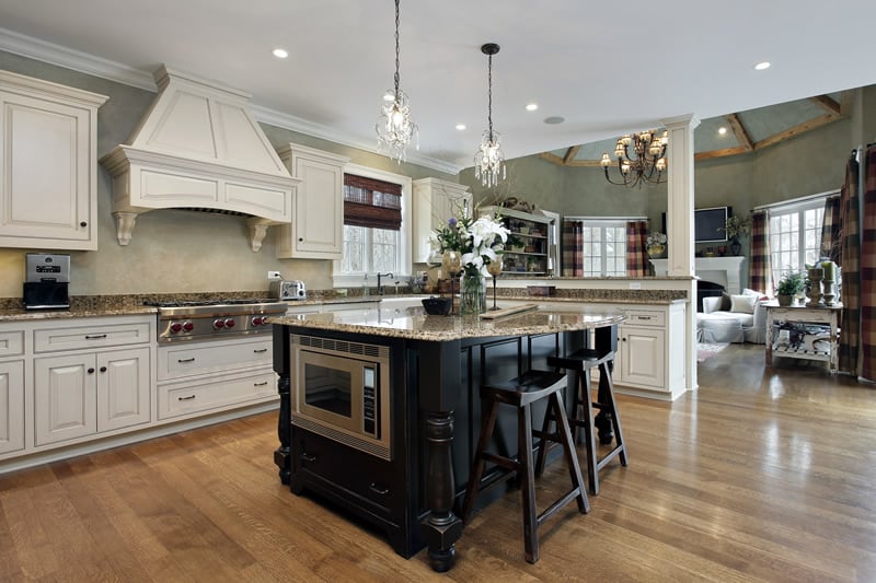 Kitchen with white cabinets and black cabinet with beige granite custom island