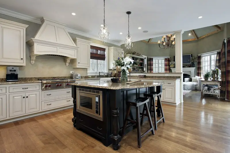 Kitchen with black cabinet and beige granite custom island