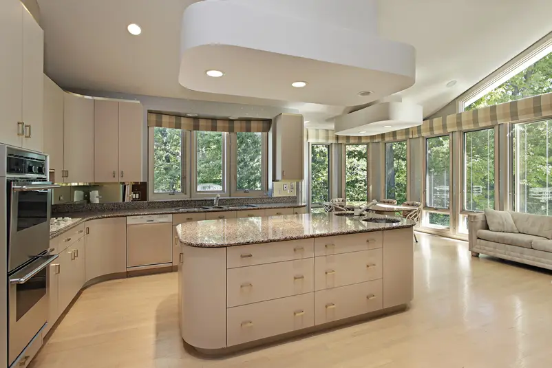 Kitchen with large rounded corner island and cream cabinets