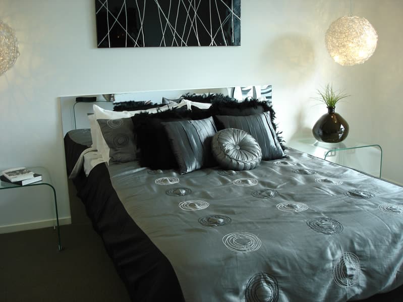 Bedroom with black grey bed covering and white hanging ball lamps