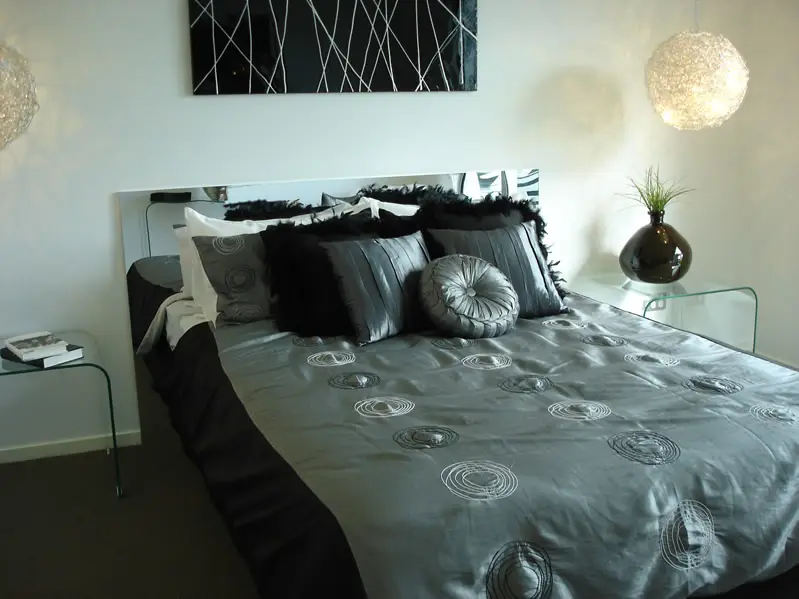 Bedroom with black grey bed covering and white hanging ball lamps