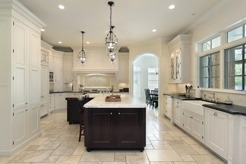 Upscale kitchen with marble counter island and white cabinets paired with dark countertops