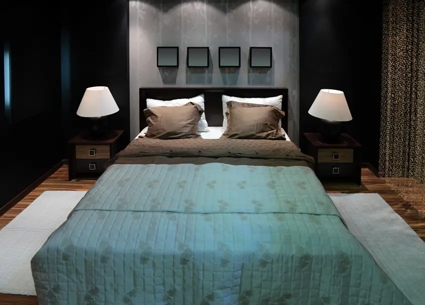 Bed with green comforter, white rug and concrete wall
