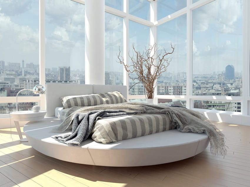 Tall windows with white frames, circular bed and view of the city