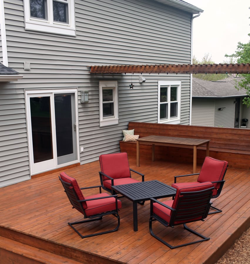 Backyard deck with pergola and red chairs and black table
