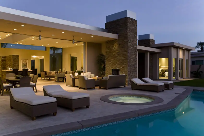 Pool with flagstone decking, wicker chairs and floor to ceiling windows