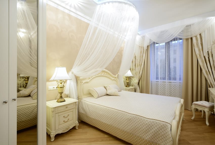 Beautiful white bedroom with sheer bed curtains