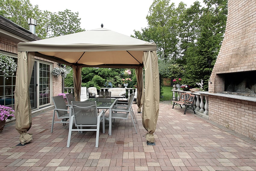 Open patio uses brick pavers in basket-weave patter with large outdoor brick barbeque