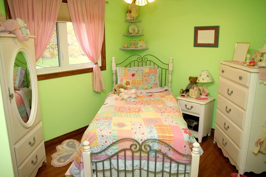 Green room with candy pink drapes and pastel colored patchwork bedding
