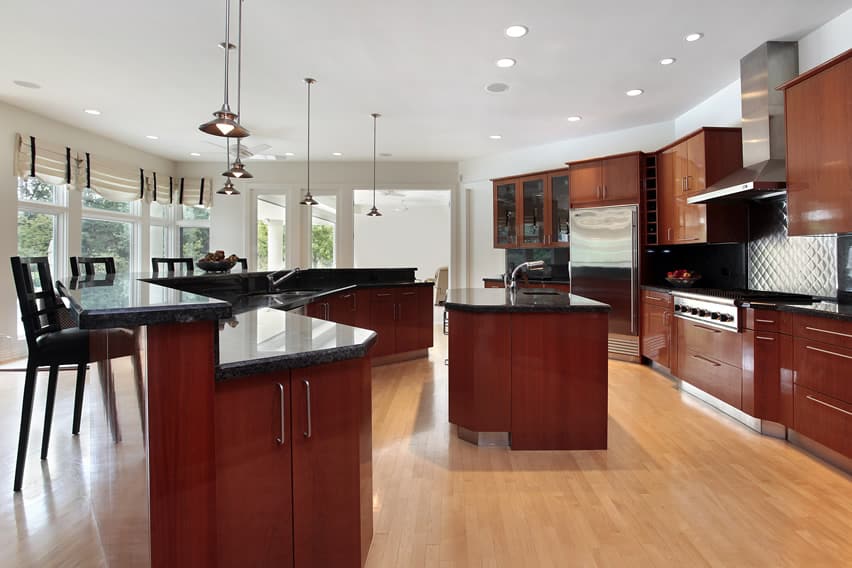 Cherry wood kitchen with black granite countertops and light wood flooring