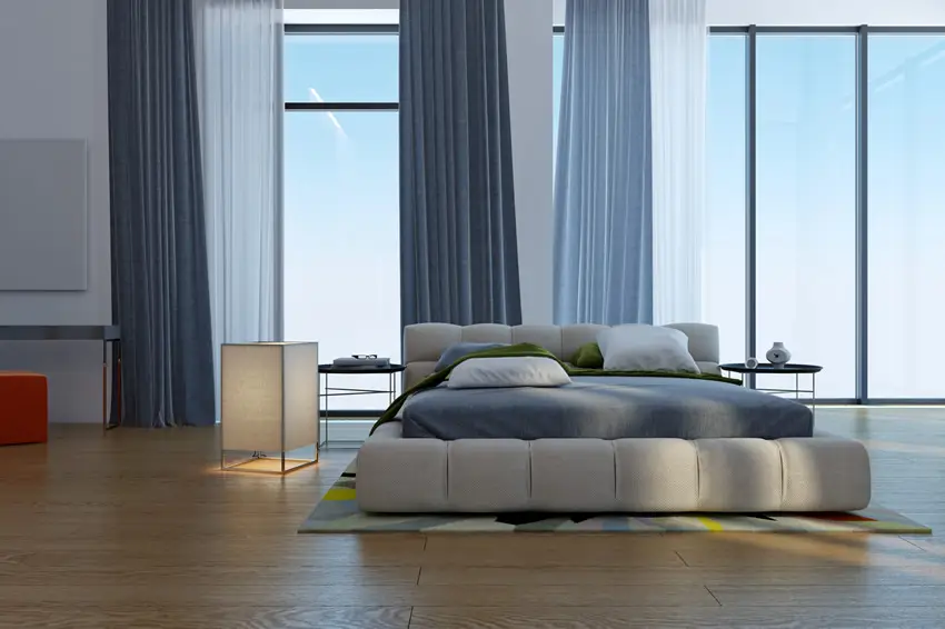 Room with floor to ceiling curtains, high ceiling and futon bed
