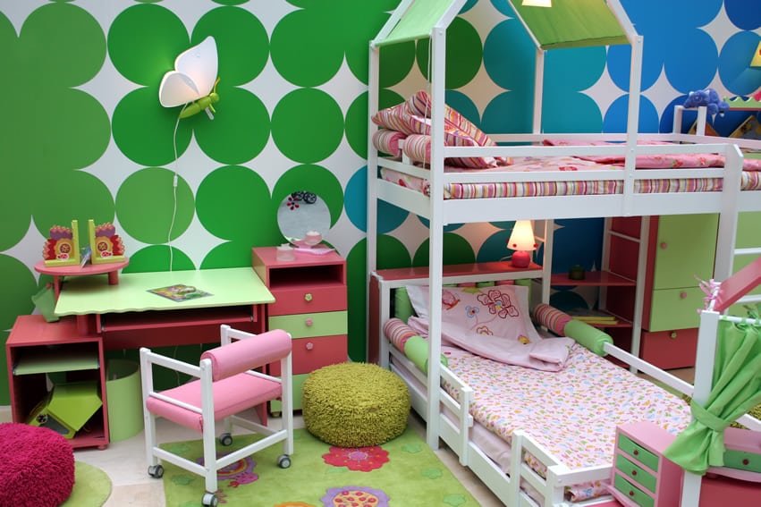 Room with bold green patterns, white beds and kid desk