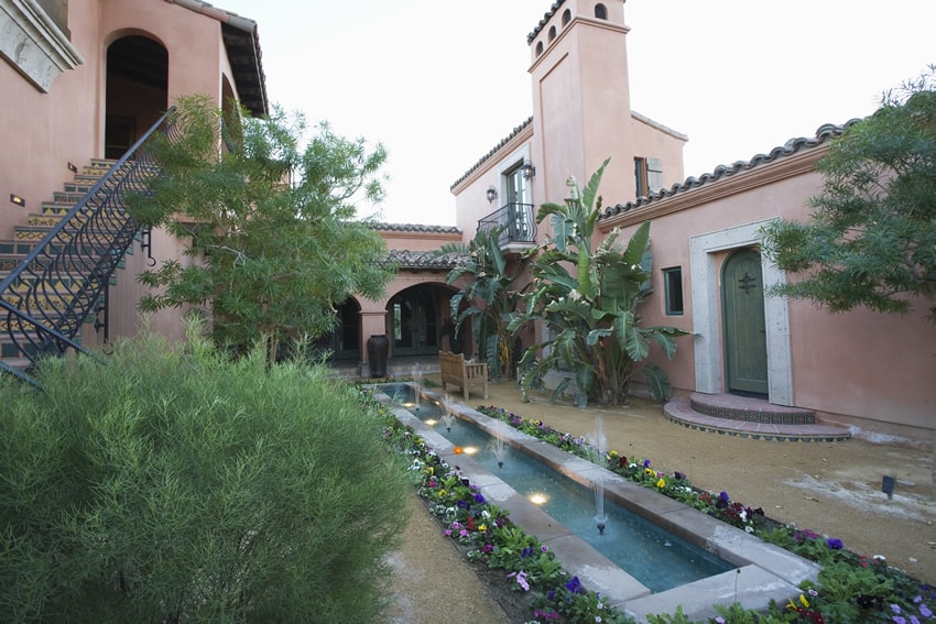 Courtyard surrounded by flowers and rectangular water fountain