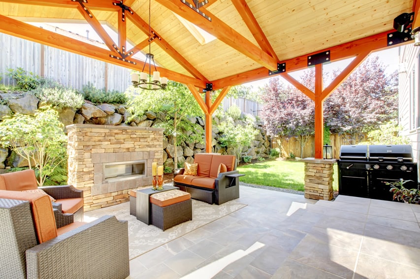 Covered patio area with large, square-cut natural stone tiles and outdoor fireplace