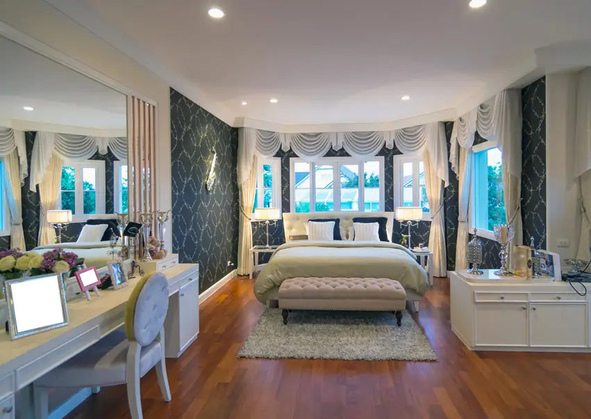 room with dark green patterned wallpaper and pink tufted bench