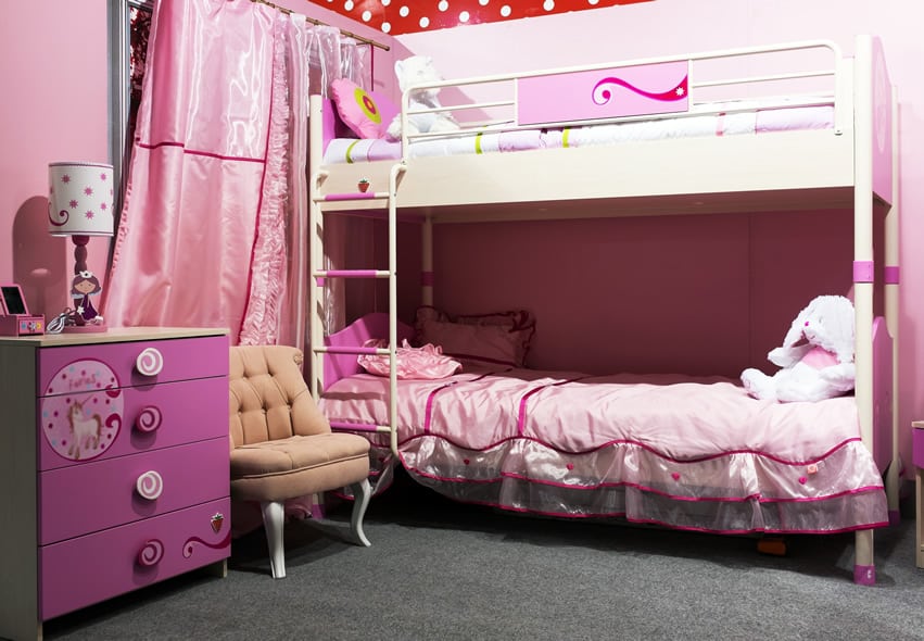 Bed with soft frills, pink hued satin curtains and drawers with whimsical handles