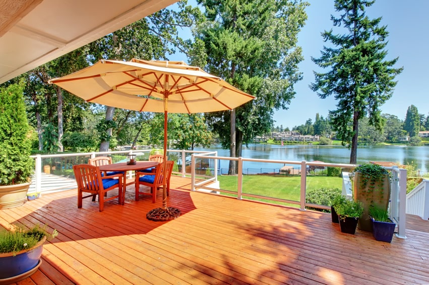 Wood deck with beautiful lake view and outdoor patio furniture with umbrella
