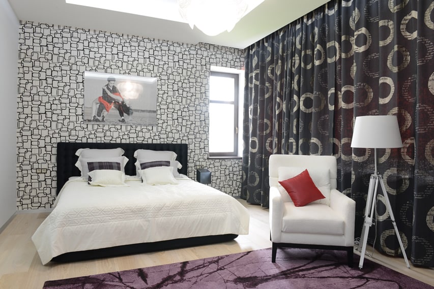 Bedroom with geometric patterned wall, printed curtains and white club lamp