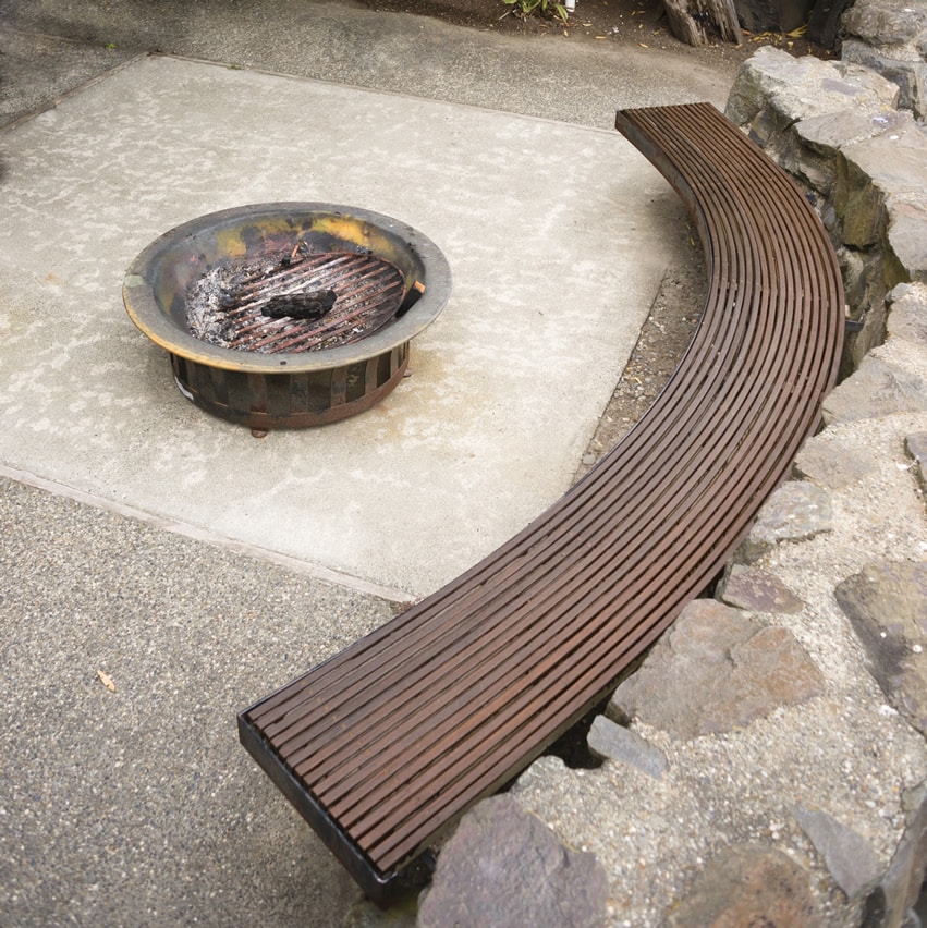 Fire pit on concrete patio with curved wood bench