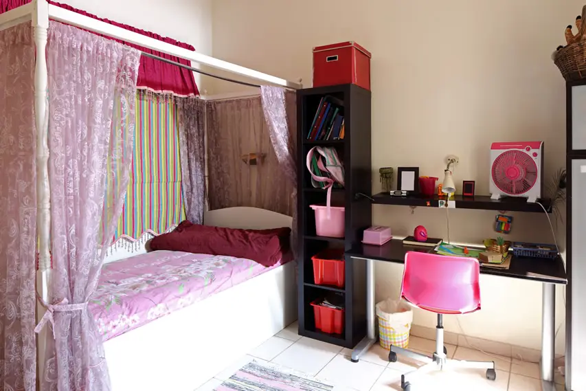 Girls small bedroom with whimsical curtain and school desk area