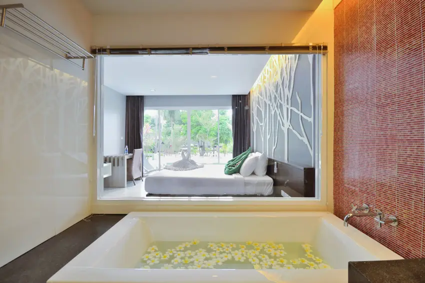 Bathtub with mural wall and view of the bedroom