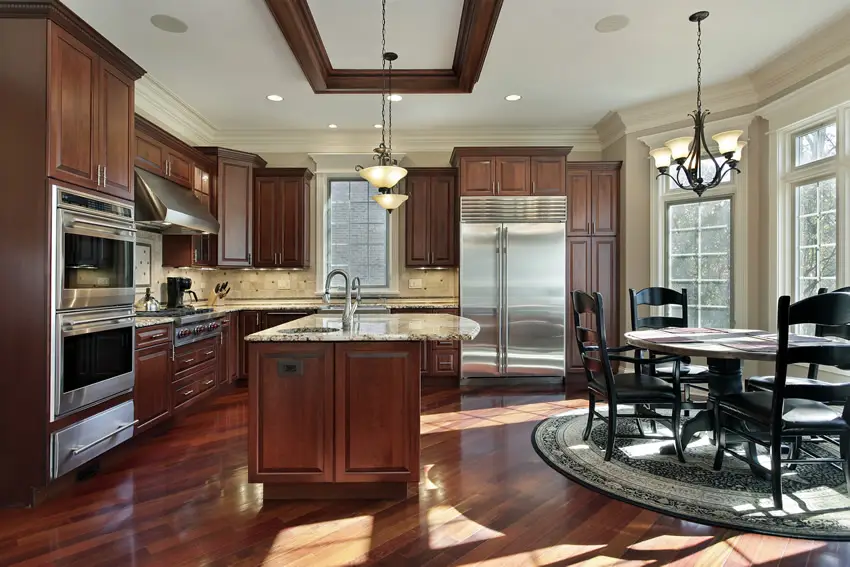 Kitchen with built in ovens, round carpet and wooden furniture pieces in black stain