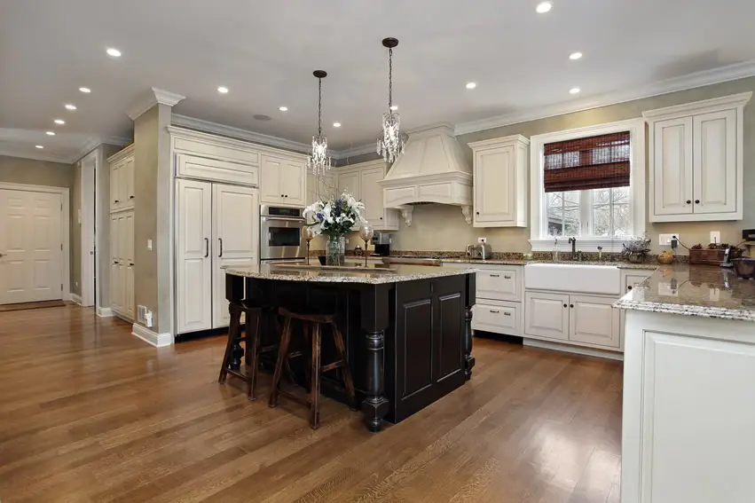 Kitchen with rows of recessed lighting, bar stools and salt and pepper colored countertop