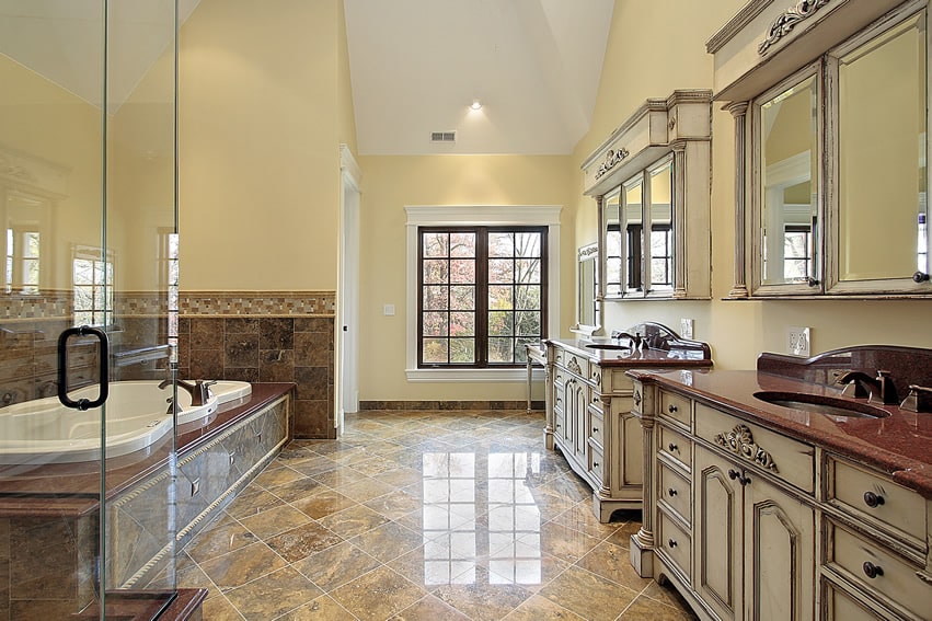 Large bathroom with spacious ceiling feature. Walls painted in bright light yellow with white moldings, and furniture in antiqued white finish.