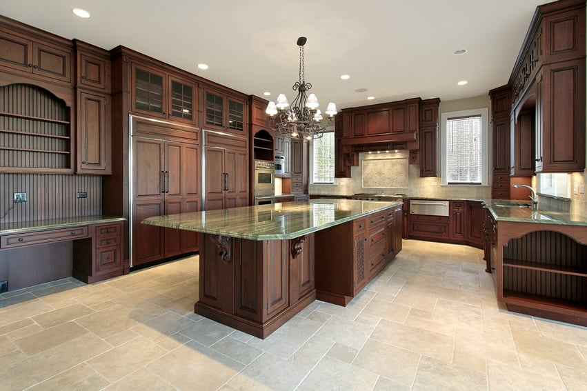 Large custom kitchen with dark walnut wood cabinets and green granite countertops with large island