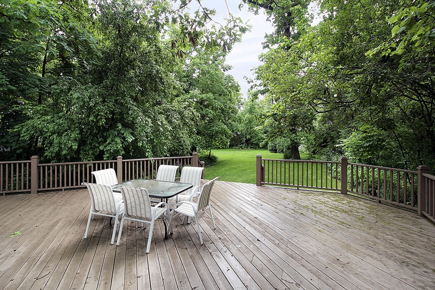 Large wood deck with railing and view of backyard trees