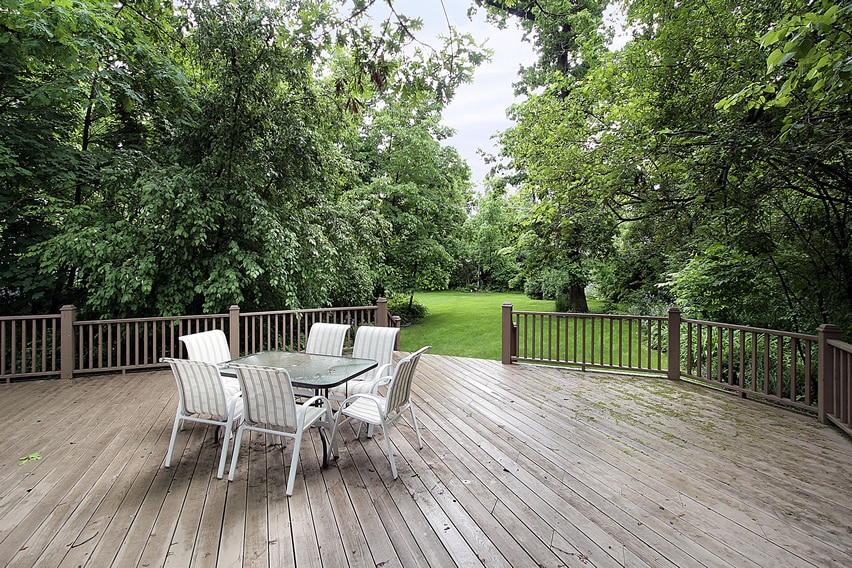 large wood deck with railing view of backyard trees