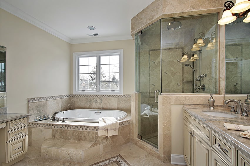Bathroom combines light tan walls with natural stone tiles. Mosaic tiles used as borders and accents for the floor