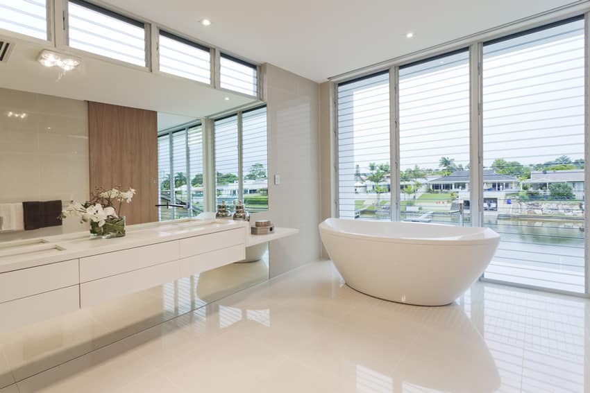 Bathroom with glazed Italian tiles, high ceiling and window with wood slats