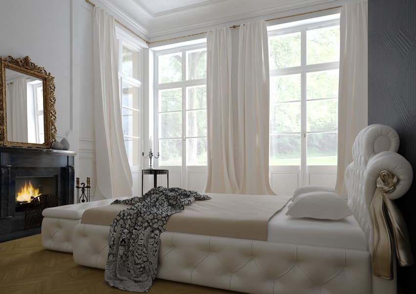 Bedroom with pine floors, tufted bed and fireplace