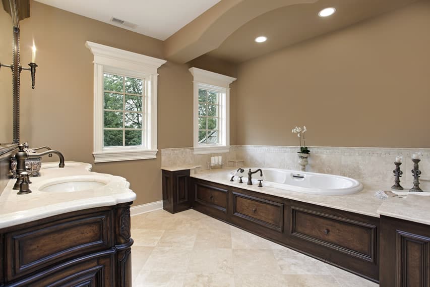 Bathroom with warm brown walls and moldings with porcelain tile flooring and white granite countertop