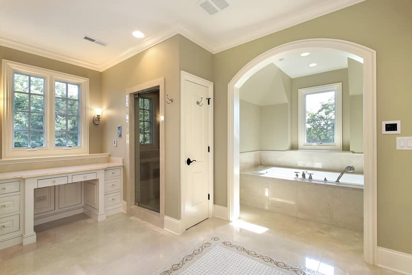 Large bathroom uses light-colored polished porcelain tiles with white arched room for tub