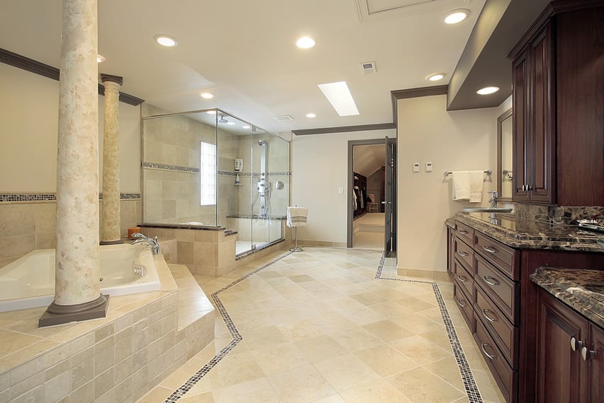 Large bathroom uses natural stone ceramic tiles with accents of dark brown mosaic stone tiles