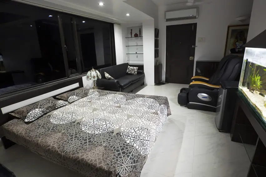 Bedroom with fish tank, black couch and ceramic tiles for the floor
