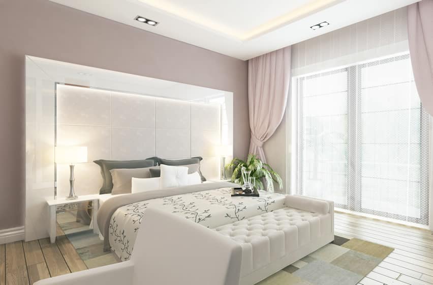 Bedroom with lilac curtains, aged wood flooring and floral printed bedding