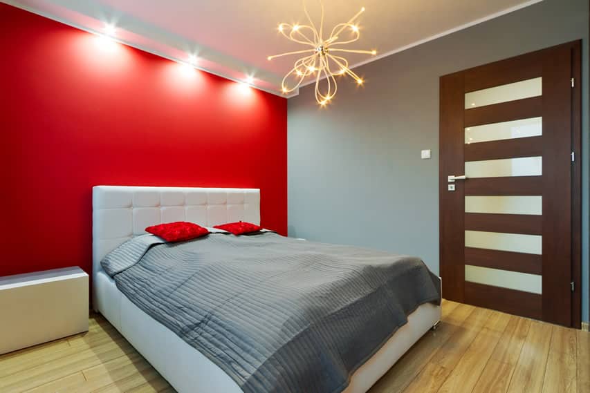 Bedroom with red walls white headboard and sputnik chandelier