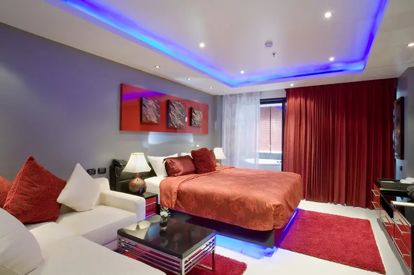Room with red curtains, bed and pillows and white sectional