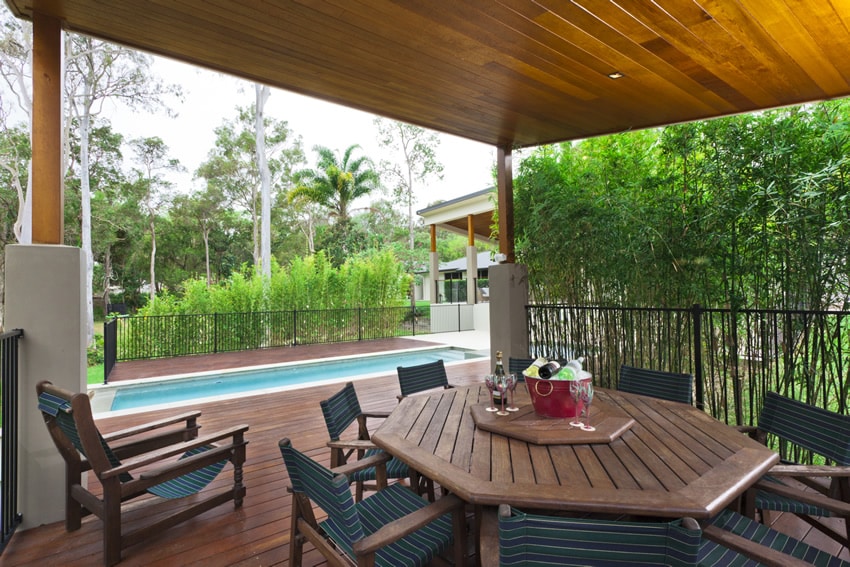 Tropical themed pool-side covered patio uses PVC decking with outdoor dining area