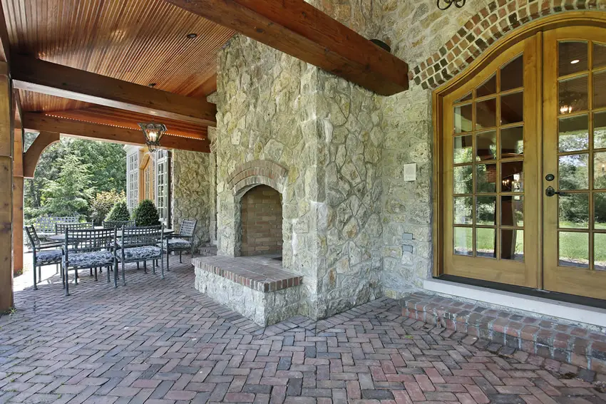 Beautiful patio with red brick pavers and rustic outdoor stone fireplace