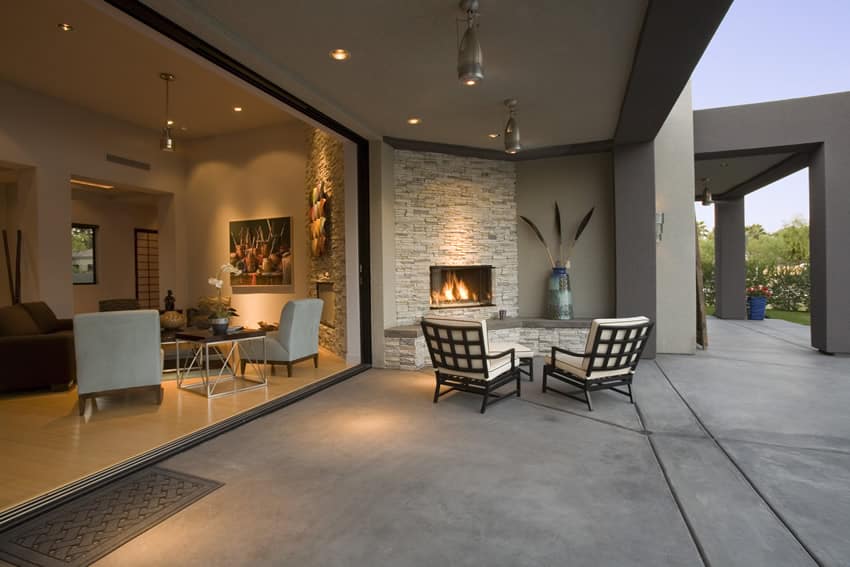 Spacious modern patio area with poured concrete flooring outdoor rock fireplace