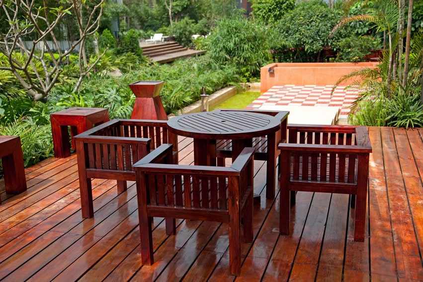 Stained wood deck with lush garden backyard