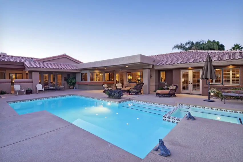 Raw concrete poolside flooring with white in-pool tiles with closed umbrella