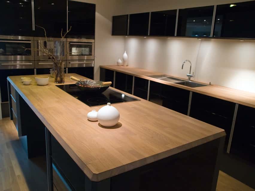 Trendy modern kitchen with high gloss black cabinets and wood butcher block wood countertops